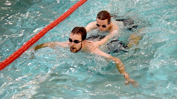 Zwei junge Männer schwimmen in einem Becken.