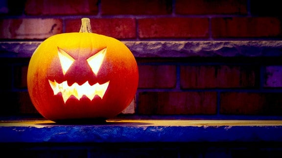 Beleuchtete Halloween-Kürbislaterne auf Verandatreppen in der Nacht