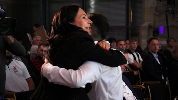 Eine Frau und ein Mann umarmen sich als Beglückwünschung.
