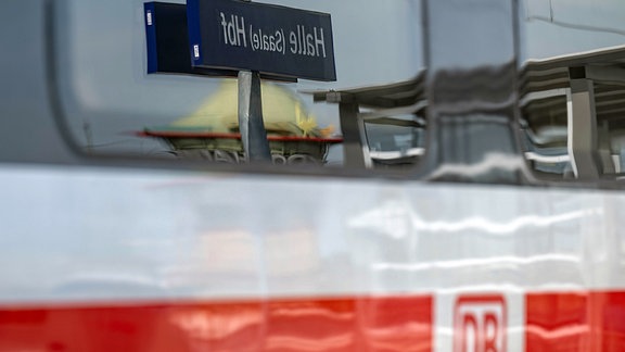 Ein Bahnhofsschild mit der Aufschrift «Halle (Saale) Hbf» spiegelt sich im Hauptbahnhof in Halle/Saale in der Scheibe eines ICE.