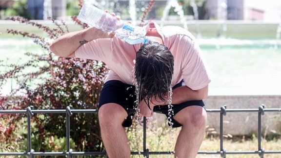 Ein Mann kühlt sich mit Wasser ab