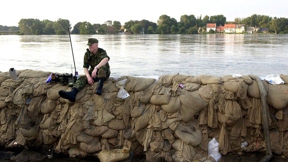 Ein Soldat der Bundeswehr sitzt am Abend des 19.08.2002 mit seinem Funkgerät auf einem Sandsackwall an der Elbe bei Schönebeck nahe Magdeburg und hält Deichwache.