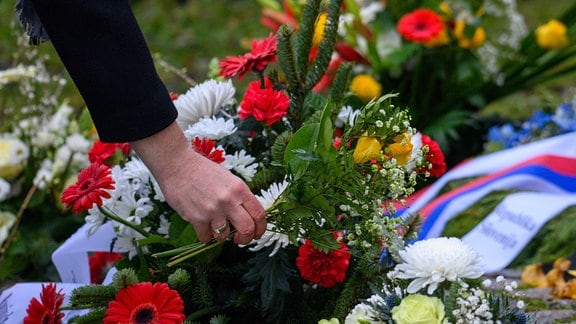 Ein Mann legt am Mahnmal Magda Blumen nieder. 