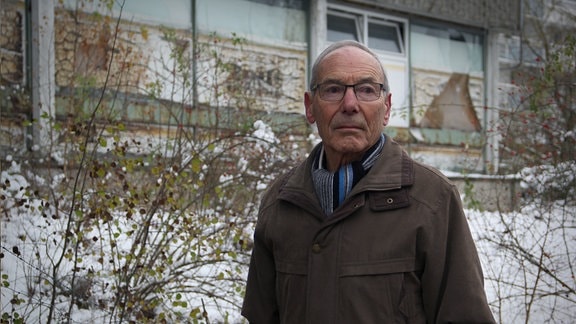 Ein Mann steht in seiner ehemaligen Wohnsiedlung in Holzdorf-Ost.