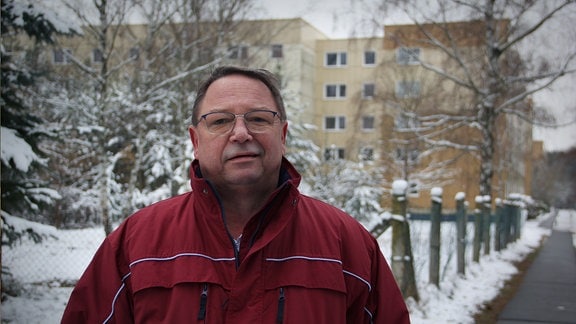 Ein Mann steht in seiner ehemaligen Wohnsiedlung in Holzdorf-Ost.