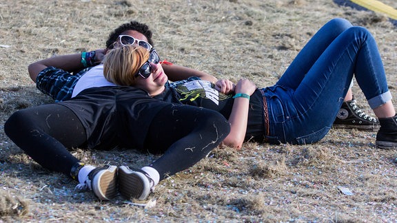 Zwei junge Leute liegen auf einer Wiese.