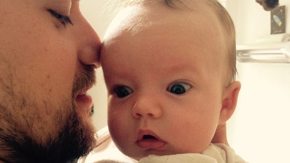 Ein junger Vater hält sein Baby zum "Bäuerchen".