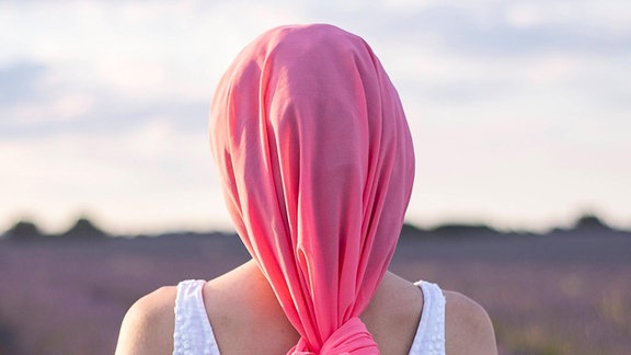 Eine Frau mit einem pinken Schal am Kopf