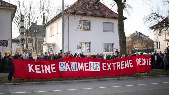 Demonstranten stehen auf dem Bürgersteig und halten ein großes rotes Banner mit der Aufschrift: "Keine Räume für extreme Rechte"