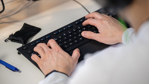 Hände arbeiten auf einer schwarzen Tastatur