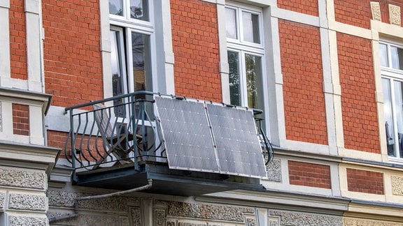 Solarmodule für ein sogenanntes Balkonkraftwerk hängen an einem Balkon in einer Altstadt.