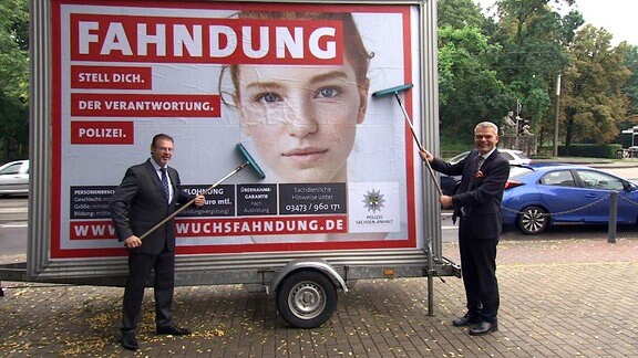 Der Rektor der Polizeifachhochschule Aschersleben, Knöppler, und Innenminister Stahlknecht bringen ein Plakat an, das für die Polizei werben soll