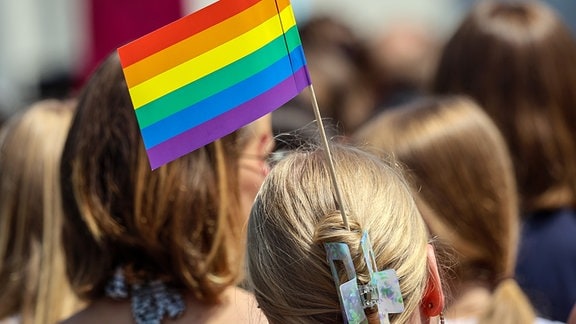 Eine Teilnehmerin trägt eine Regenbogenfahne im Haar beim Umzug zum Christopher Street Day (CSD)