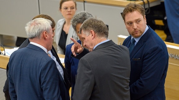 Daniel Neugebauer, Kandidat für das Amt des Landesbeauftragten für Datenschutz des Landes Sachsen-Anhalt steht neben diskutierenden Landtagsabgeordneten im Plenarsaal.