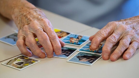 Die Hände einer älteren Person auf einem Memory-Spiel