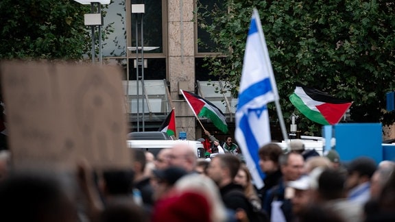 Fahnen einer pro-palästinensischen Demonstration sind im Hintergrund einer pro-Israel-Demonstration zu sehen.