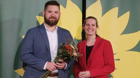 Dennis Helmich und Madleine Linke, Vorsitzende von Bündnis 90 Die Grünen Sachsen-Anhalt, stehen auf einer Bühne. 