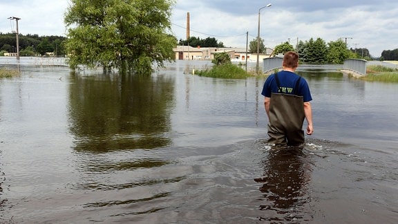 Ein Helfer vom Technischen Hilfswerk läuft durch von Hochwasser überflutetes Gebiet