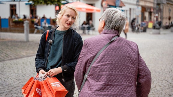 Eine blonde Frau unterhält sich mit einer älteren Dame auf der Straße
