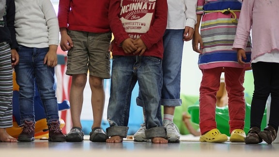 Kindergartenkinder stehen zusammen. Im Bild: Beine und Hände