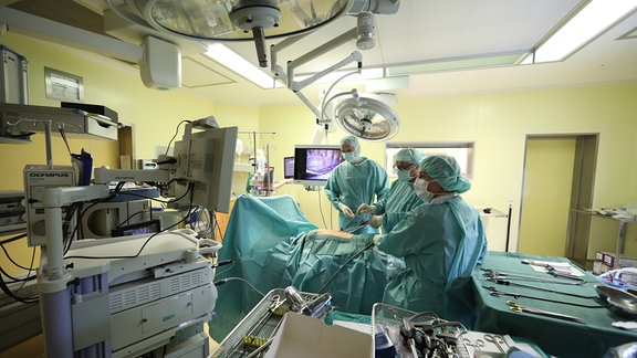 Ärzte und Schwestern stehen bei einer endoskopischen Operation in einem Operationssaal im SRH Waldklinikum. Hier wird bei einer Operation einem Patienten Lymphknoten an der Lunge entfernt.