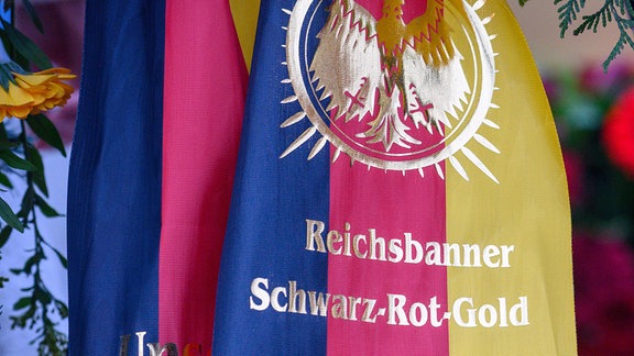 "Reichsbanner Schwarz-Rot-Gold" steht auf einer Schleife an einem Kranz. 