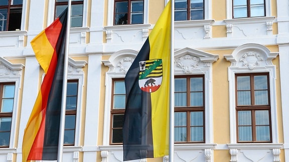 Flaggen von Sachsen-Anhalt und Deutschland vor einem Gebäude.