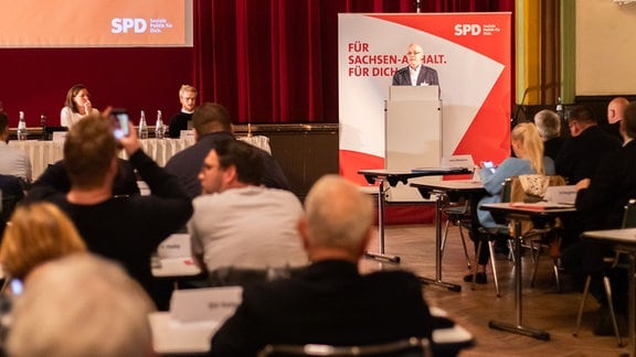 Ein Mann steht an einem Rednerpult vor Publikum, im Hintergrund ein SPD-Banner