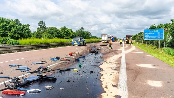 Eine große Öllache und Trümmerteile liegen nach einem Unfall auf der Fahrbahn einer Autobahn