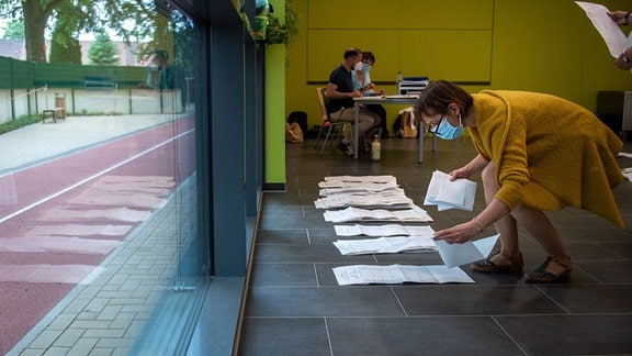 Wahlhelfer sortieren Stimmzettel zum Beginn der Auszählung von Stimmen bei der Landtagswahl von Sachsen-Anhalt in einer Schule in Magdeburg.