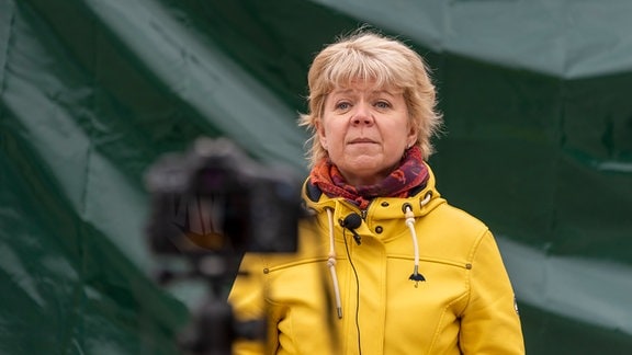 Die Spitzenkandidatin der Grünen, Cornelia Lüddemann, steht vor einem verhüllten Wahlplakat, neben ihr eine Kamera.
