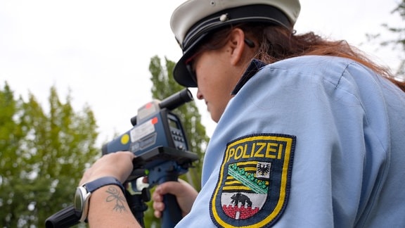 Polizeihauptmeisterin Peggy Schmidt misst bei der Verkehrskontrolle die Geschwindigkeit der Fahrzeuge in einer 30er-Zone am Ortsausgang von Zörbig.