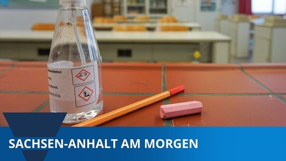 In einem Chemie- Klassenraum einer Schule liegt ein Stueck Kreide, ein Stift und eine Sprühflasche, die mit Desinfektionsmittel gefuellt ist, auf einem Tisch. 