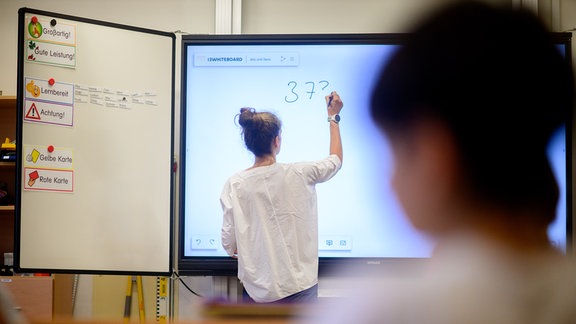 Ein Lehrerin schreibt eine Mathematikaufgabe auf eine digitale Schultafel im Klassenraum einer 4. Klasse einer Grundschule in der Region Hannover. Für Hunderttausende Schülerinnen und Schüler in Niedersachsen und Bremen startet am Donnerstag das neue Schuljahr nach den sechswöchigen Sommerferien.