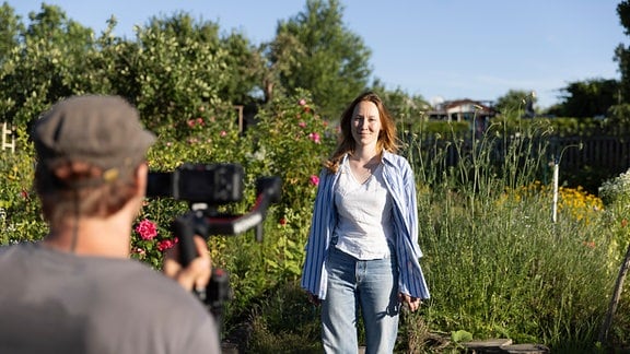 Eine junge Frau in ihrem Garten in Halle (Saale), die von einem Kameramann gefilmt wird.