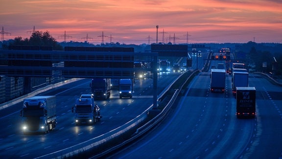 Lastwagen und Autos rollen bei Sonnenaufgang auf der Autobahn A2