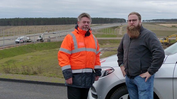 Zwei Männer an einer Autobahnbaustelle.