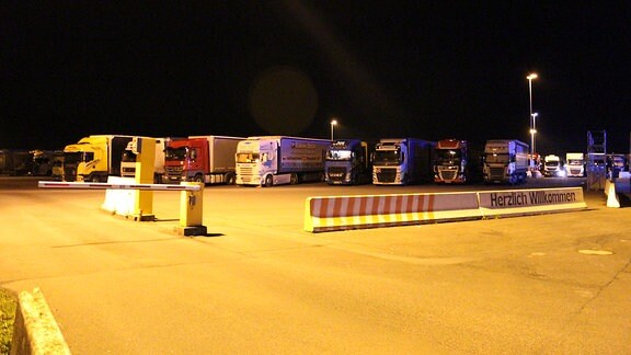 Ein Autobahn-Parkplatz voller Lkw bei Nacht 