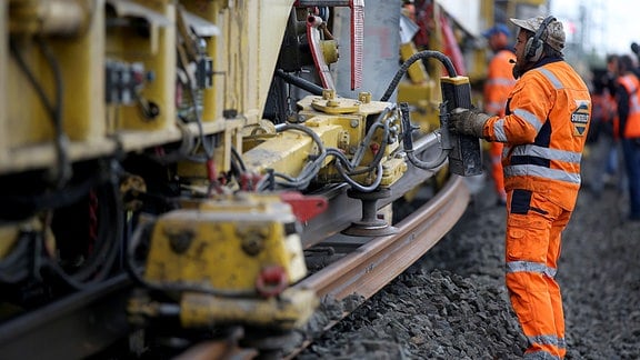 Ein Arbeiter überwacht an einem 700 Meter langer Gleisumbauzug die Verlegung neuer Schienen