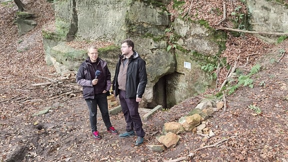 Zwei Männer stehen vor Felsen
