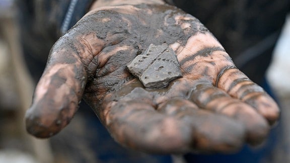 Eine 7000 Jahre alte Scherbe, die am Fundplatz einer 7500 Jahre alten Siedlung ausgegraben wurde, liegt in der Hand einer Archäologiestudentin