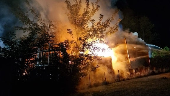 Feuerwehr bei Löscharbeiten an einer brennenden Lagerhalle