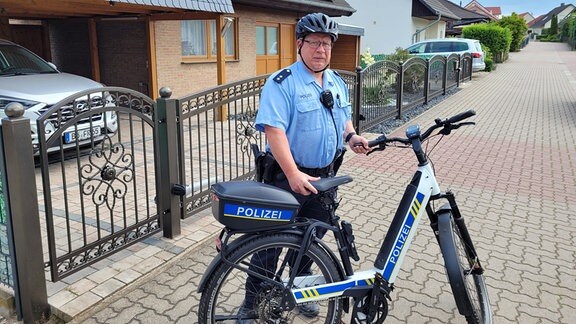 Der Polizist Dirk Böschel steht neben seinem Dienstfahrrad in einer Straße, in der er ermittelt.