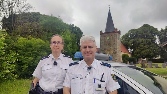 Die Polizisten Susanne Scharf und Jens Ruhnke vor einer Kirche.