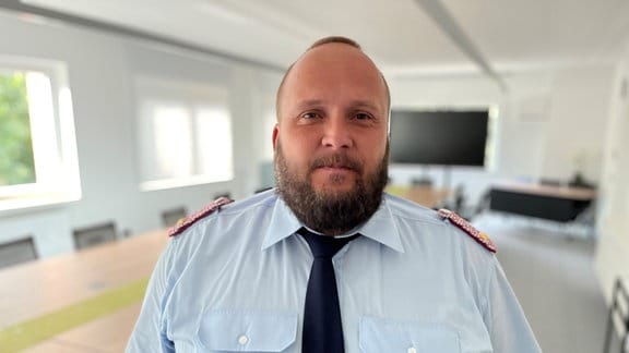 Einsatzleiter Stefan Libbe steht Feuerwehruniform in einem Besprechungsraum.