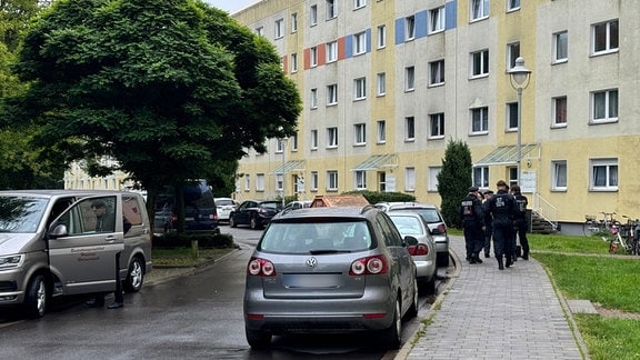 Polizisten und ein Fahrzeug eines Bestattungsunternehmen stehen in der Nähe des Einsatzorts, der möglichwerweise im Zusammenhang mit der Attacke in Wolmirstedt steht. 