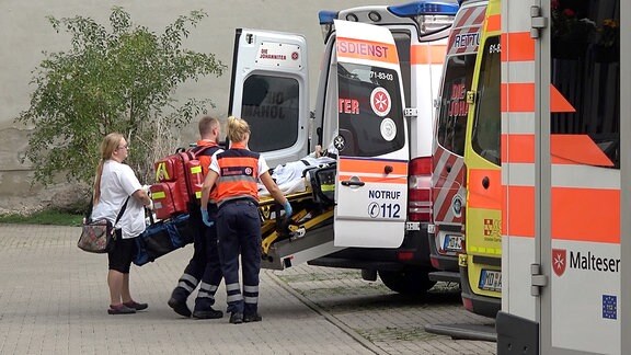 Zwei Sanitäter schieben eine Person auf einen Krankenbett in einen Rettungswagen