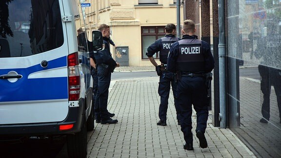 Mehrere Polizisten stehen vor einer Haustür