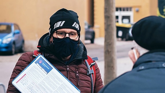 Ein Mann mit Mütze und Corona-Maske sammelt Unterschriften für einen Bürgerentscheid zum Thema sicherer Radverkehr in Magdeburg. 