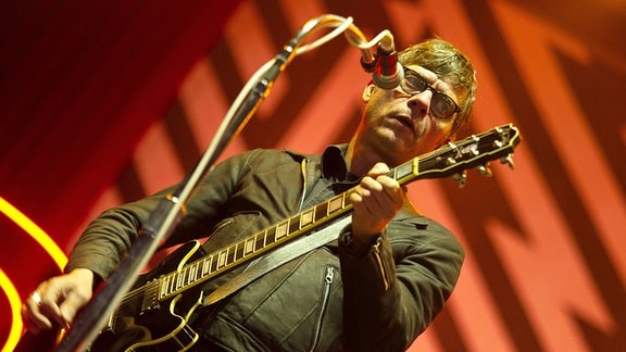 Bernd Kurtzke, ein Mann mit Brille und Gitarre steht auf einer Bühne